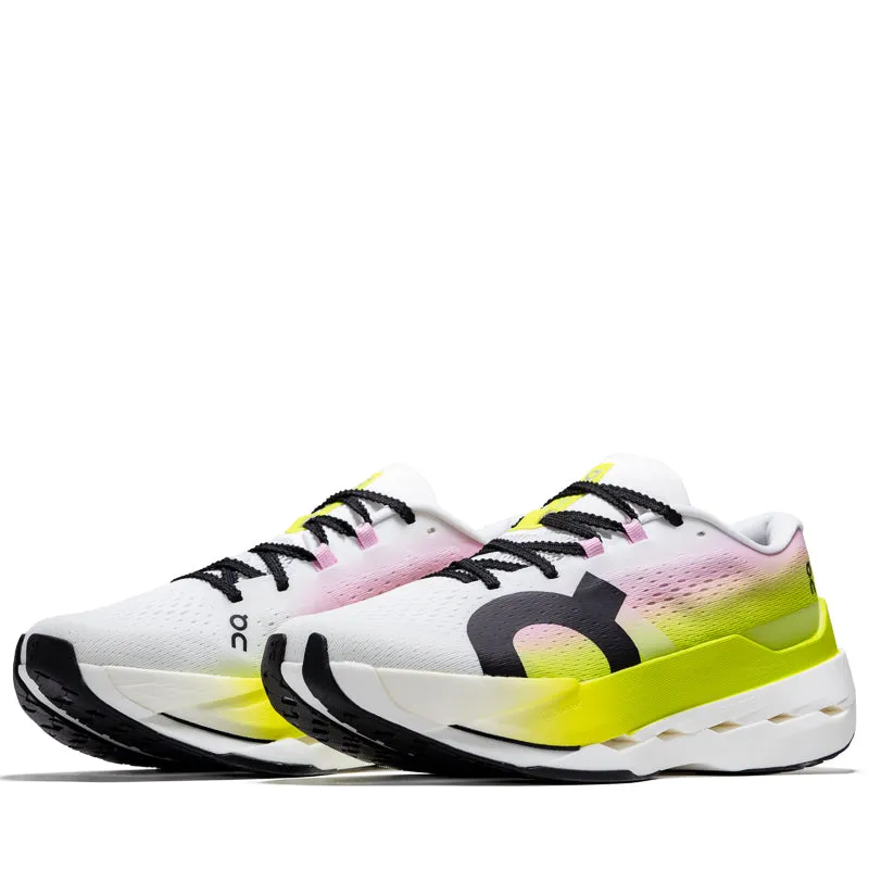On Cloudboom Max - Lime/Raspberry running on a grass track shoes